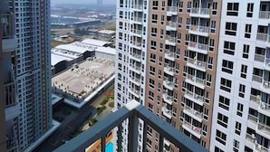 Ein Hochhaus mit mehreren Balkonen, freiem Blick auf die Stadt und einer entfernten Wasserfläche.