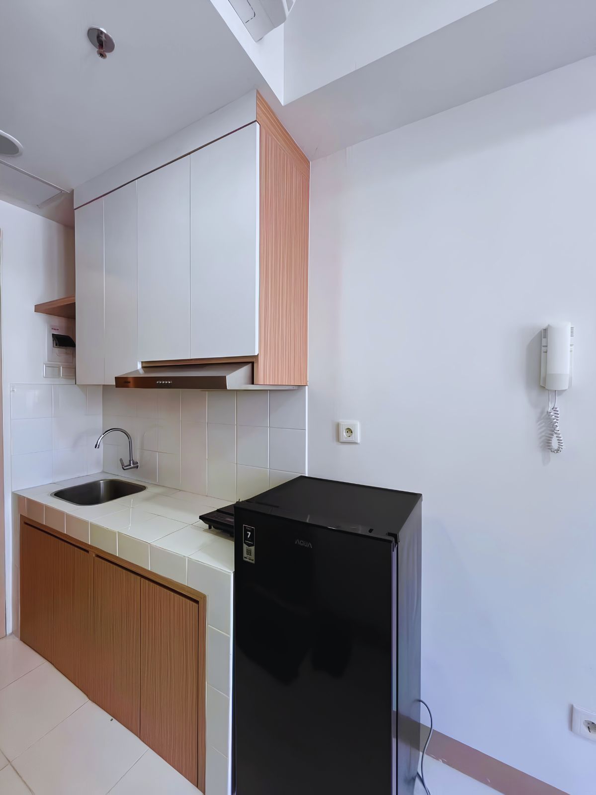 Une cuisine moderne avec des meubles blancs, un réfrigérateur noir et un évier en acier inoxydable.
