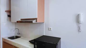 A modern kitchen with white cabinets, a black refrigerator, and a stainless steel sink.