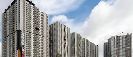 Un complejo de edificios residenciales altos con varios edificios de apartamentos, cielo despejado y una calle con conos de tráfico.