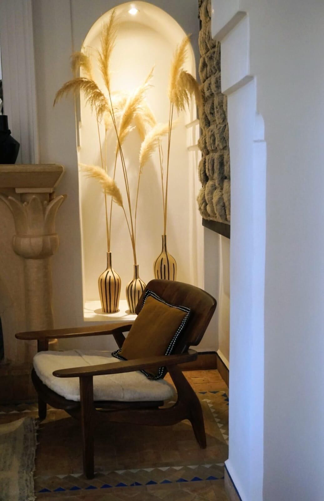 A lounge area with a sofa, decorative vases, and tall plants.