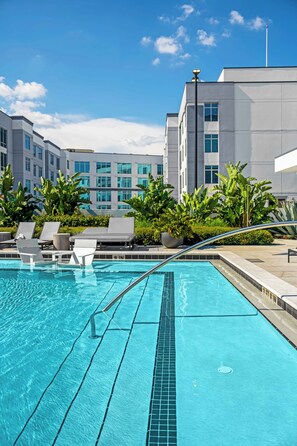 A swimming pool with clear blue water, surrounded by lounge chairs and potted plants. - The Selena - Luxury Condo w/ Rooftop Pool, Gym (Orlando)