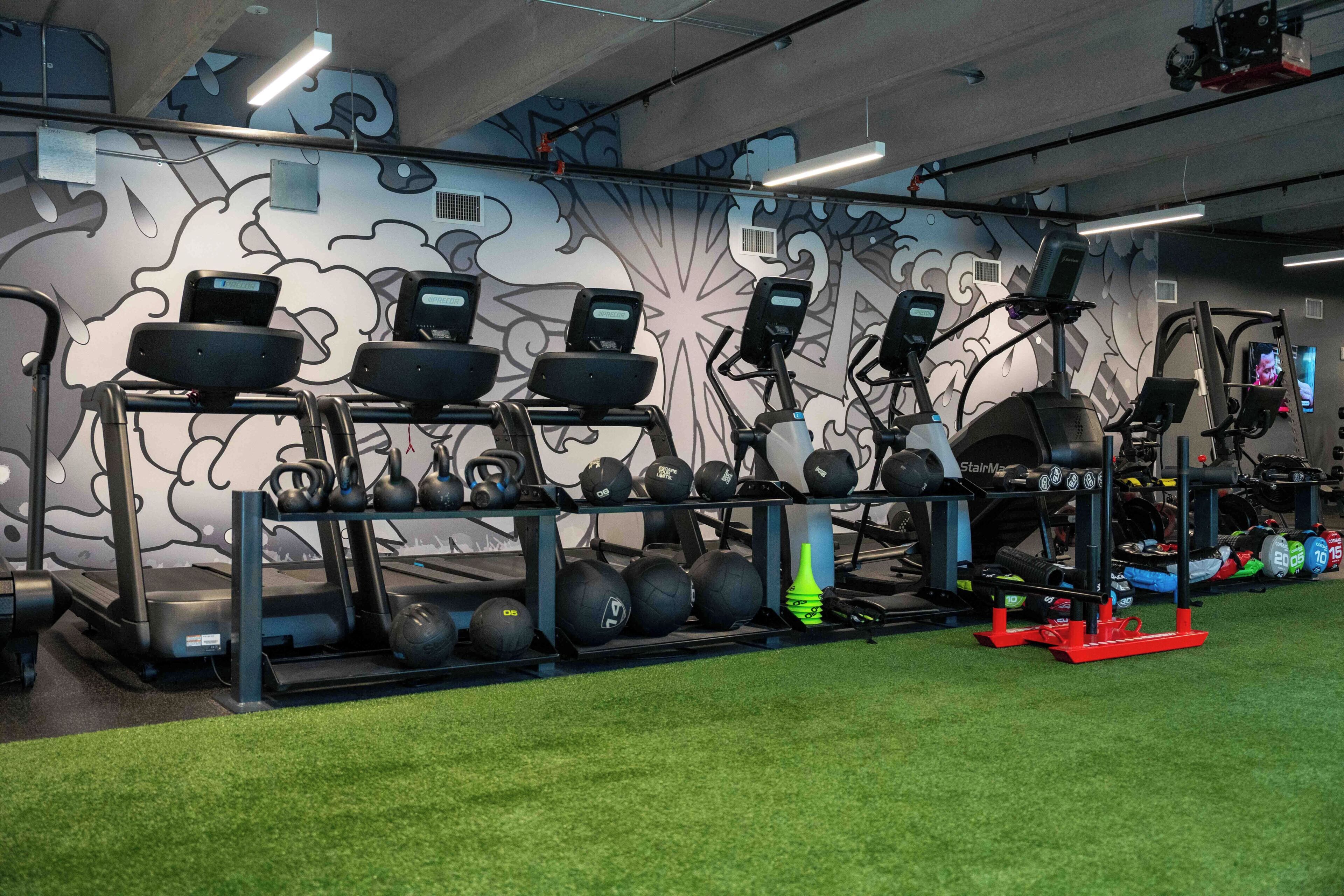 Un gimnasio con cintas de correr, bicicletas estáticas y una variedad de pesas y balones.