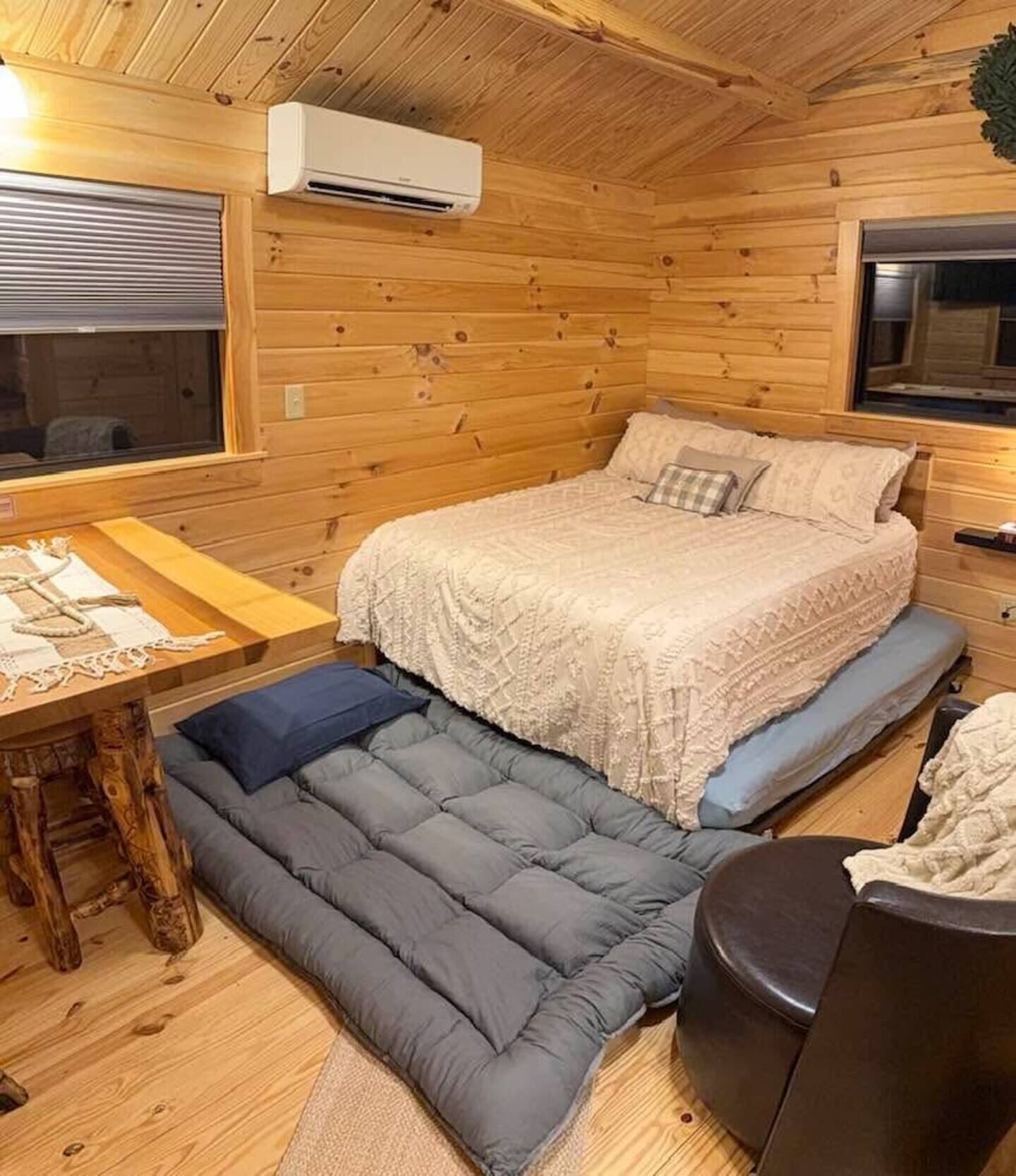 A cozy cabin interior with a bed, a small table, and a bench.