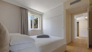 Un dormitorio con una cama individual, una ventana con cortinas y una puerta que da a otra habitación.