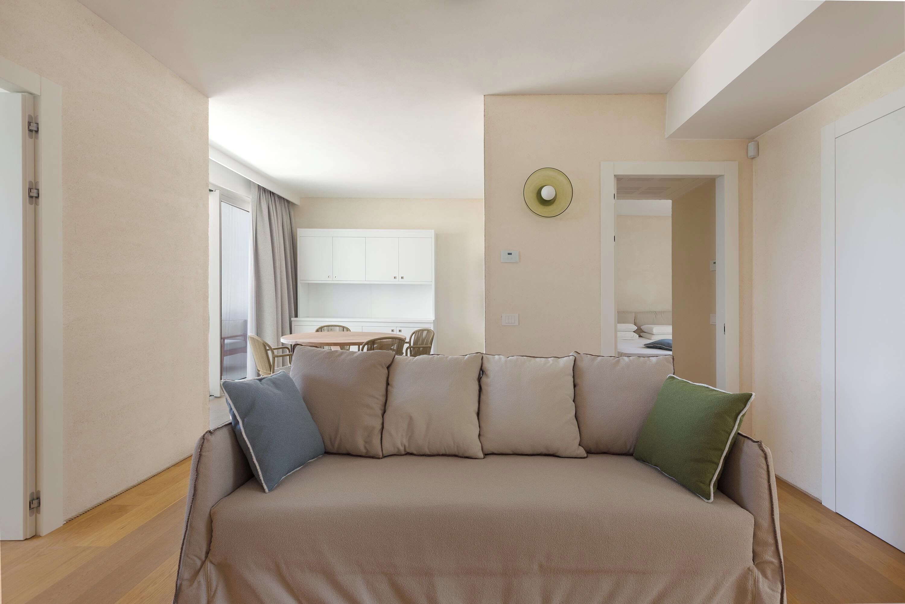 A modern living room with a sofa, a dining area, and a kitchen in the background.