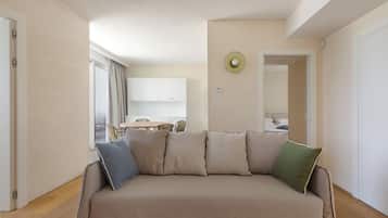 A modern living room with a sofa, a dining area, and a kitchen in the background.