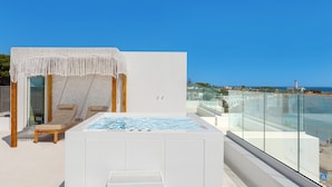 A rooftop terrace with a hot tub, seating area, and a view of the beach.