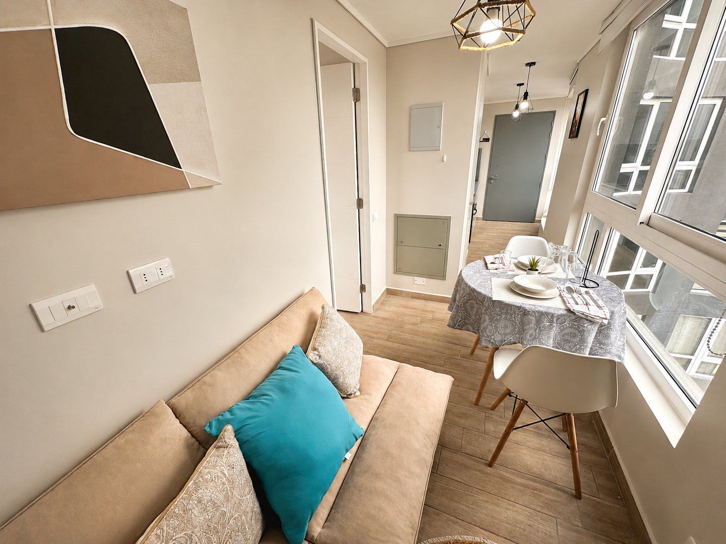 A modern living room with a sofa, a dining table, and a kitchen area with a window.