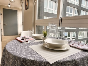 A neatly arranged dining area with a table set for two, a pitcher, a glass, and a small plant on the windowsill. - Oceana Suites Alamos  (Santiago)