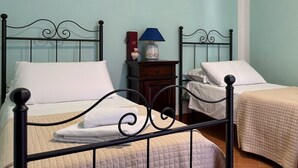 Une chambre avec deux lits, chacun agrémenté d’un oreiller blanc et d’une serviette blanche pliée. On y trouve une table de chevet avec une lampe et un objet décoratif.