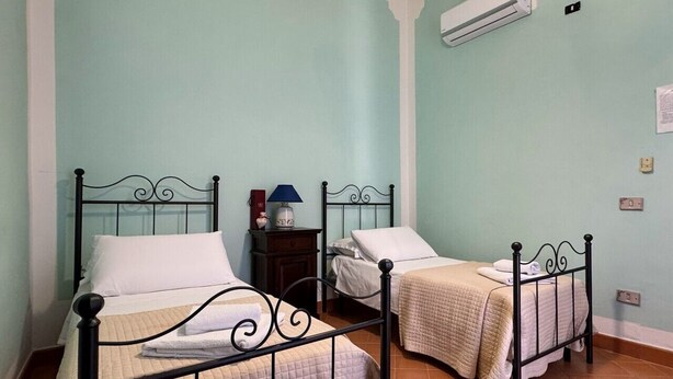 Une chambre avec deux lits, une table de chevet, un climatiseur et un interrupteur fixé au mur.