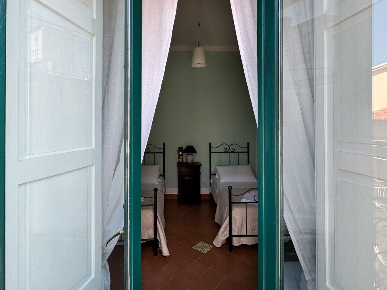 Una stanza con due letti, un comodino e una lampada a sospensione.