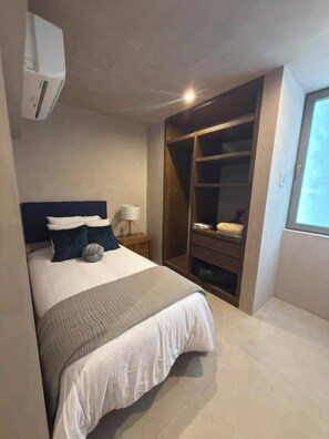Ein Schlafzimmer mit Bett, Nachttischlampe, Kleiderschrank und Fenster.