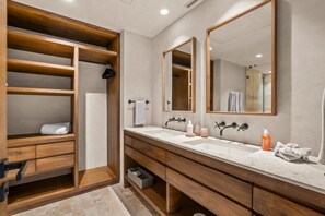 A modern bathroom with wooden cabinetry, a double sink vanity, and a large mirror. - Oceanfront Penthouse with Private Rooftop Pool (Higuera Blanca)