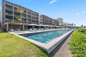 Ein modernes Hotel mit Schwimmbad, Außenbereich und einem mehrstöckigen Gebäude.