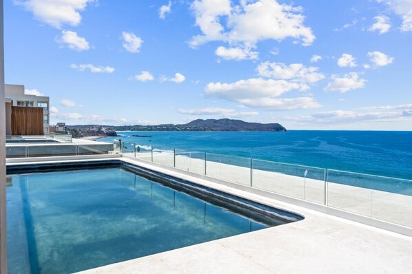A swimming pool with a clear view of the ocean and distant land. - Oceanfront Penthouse with Private Rooftop Pool (Higuera Blanca)