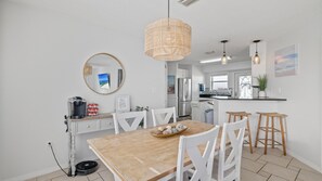 Una cucina moderna con mobili bianchi, un tavolo da pranzo in legno e una lampada a sospensione.
