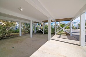 An open covered patio with white columns and a concrete floor. - Coastal Retreat- steps from the beach, pool included (Gulf Shores)