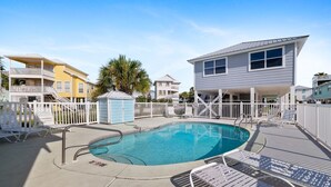 A swimming pool with a deck, lounge chairs, and a fenced area. - Coastal Retreat- steps from the beach, pool included (Gulf Shores)