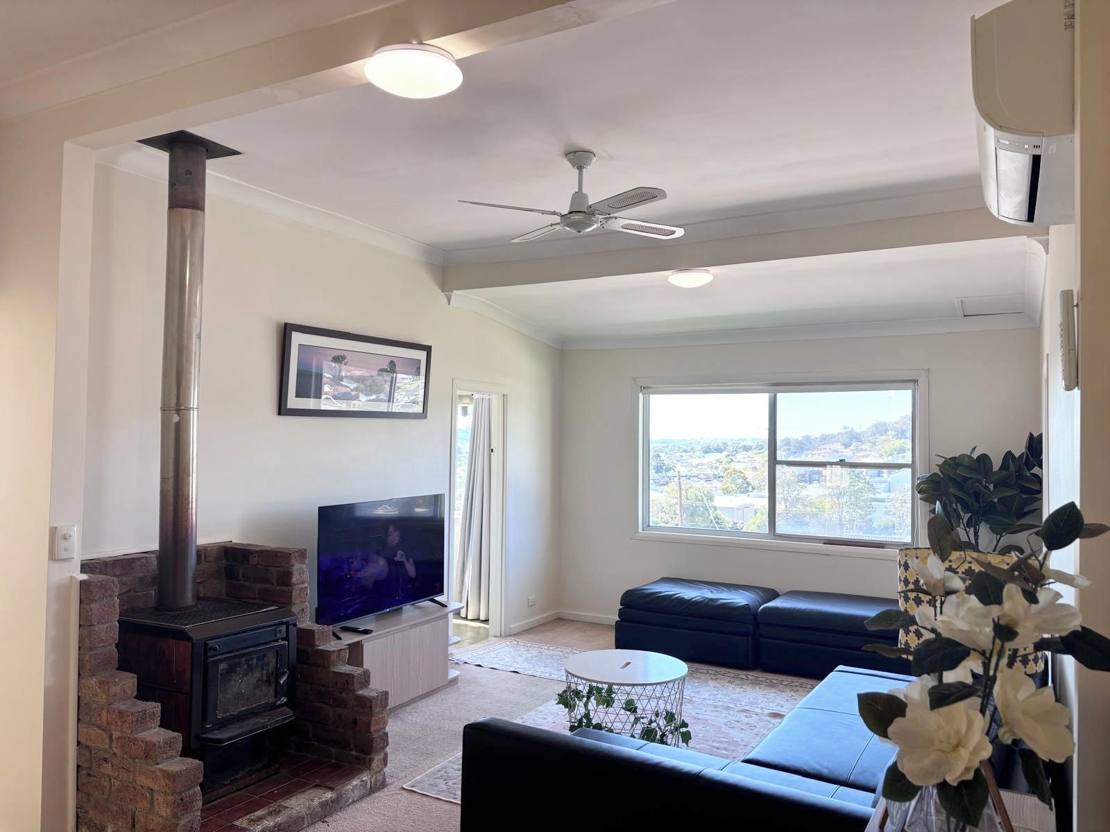 A living room with a fireplace, television, sofa, and a view through a window.