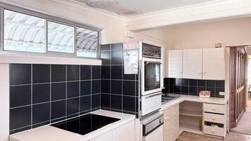 A kitchen with black and white tiles, a built-in oven, and a window with a view of the roof.