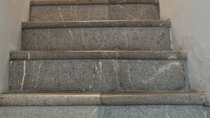 A staircase with a sign above it, a bottle on the landing, and a handrail on the right.