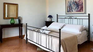 A bedroom with a bed, a nightstand, a lamp, a mirror, and a painting on the wall.