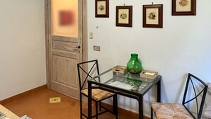 A small kitchen with a dining table, two chairs, a green vase, and a tiled floor.