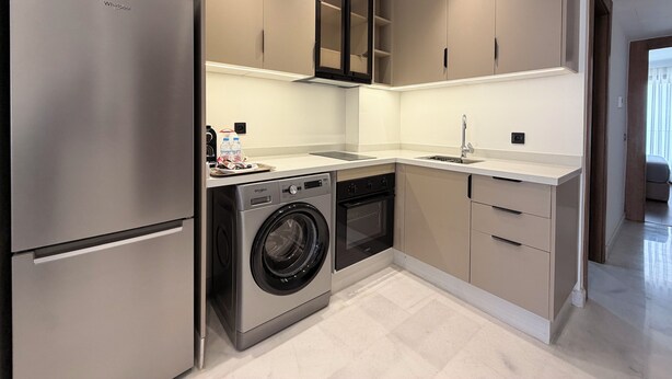 Una cocina moderna con lavadora y secadora integradas, electrodomésticos de acero inoxidable y un diseño de encimera elegante.
