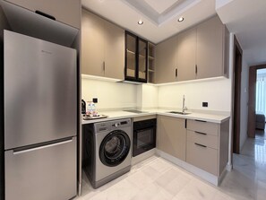 A modern kitchen with a built-in washer and dryer, stainless steel appliances, and a sleek countertop design. - Calm Maarif Palmiers Apartment (Casablanca)