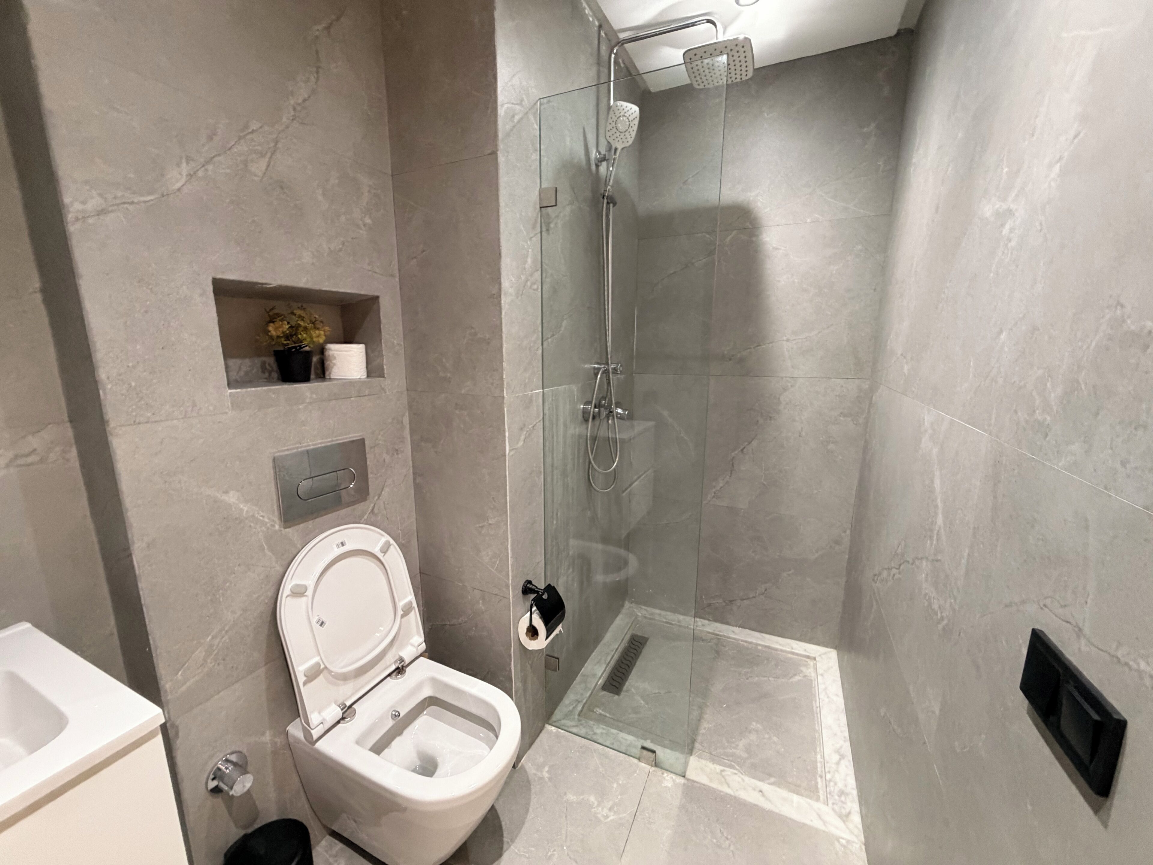 Ein modernes Badezimmer mit Toilette, Dusche und einer Duschkabine aus Glas.