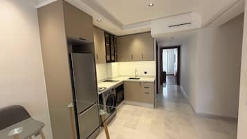 Una cocina moderna con refrigerador, lavadora y un taburete de bar de vidrio.