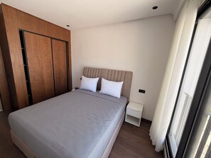 A bedroom with a large bed, wooden wardrobe, and a nightstand. - Calm Maarif Palmiers Apartment (Casablanca)