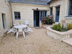 A stone building with a gravel patio, outdoor seating, and a flower bed.