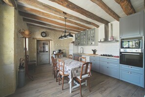 A rustic kitchen with wooden beams, a dining table with chairs, and modern appliances.
