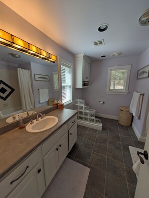 A bathroom with a double sink, vanity, cabinets, a mirror, a shower curtain, a window with blinds, and a waste basket. - Private Lakefront 3BR Retreat 2.5 Bath with private dock for your boat (Jay)
