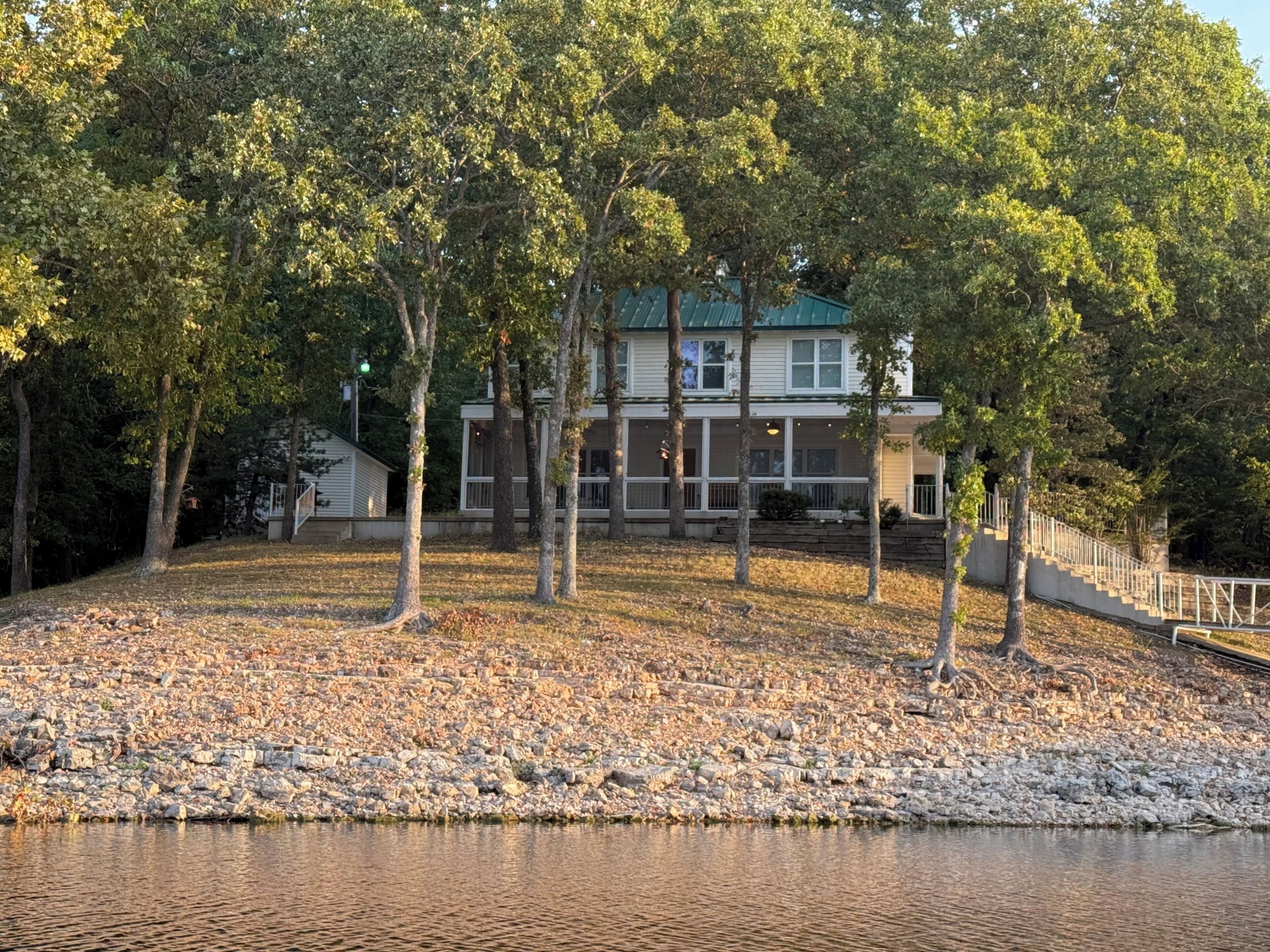En fastighet vid en sjö med ett hus, en stenlagd gång och en brygga.