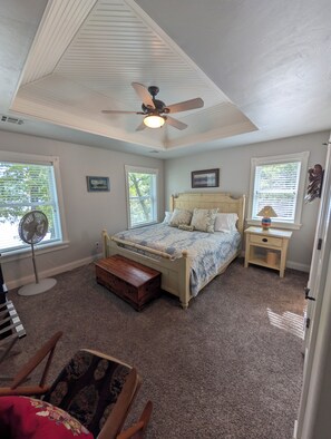 A bedroom with a bed, a bedside table, a nightstand, a fan, a window, and a ceiling fan. - Private Lakefront 3BR Retreat 2.5 Bath with private dock for your boat (Jay)