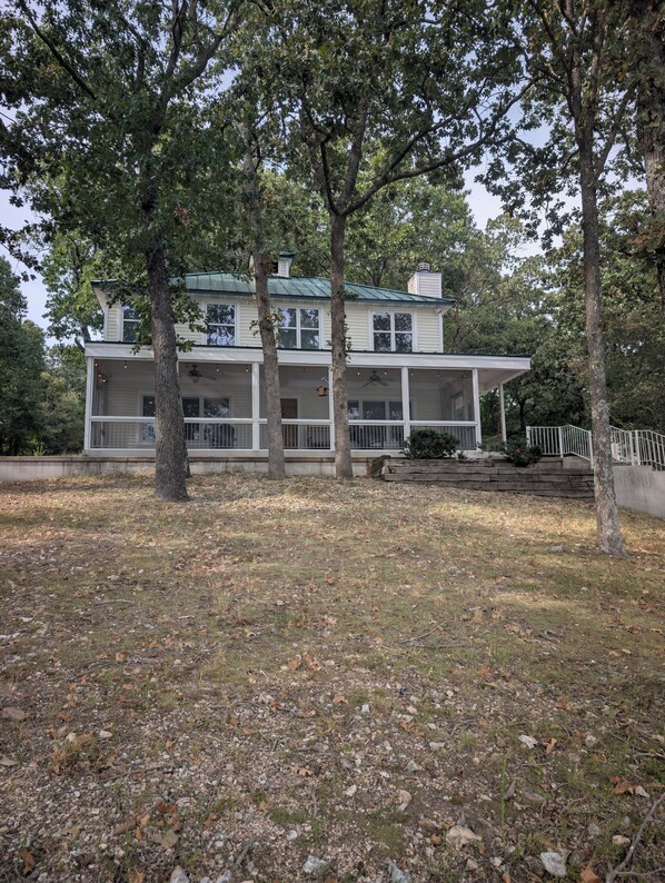 A two-story house with a porch, surrounded by trees and a grassy yard. - Private Lakefront 3BR Retreat 2.5 Bath with private dock for your boat (Jay)