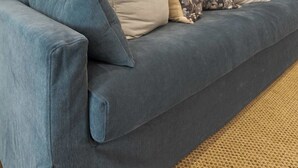 A blue sofa with multiple cushions against a plain wall, with a framed painting above it. - South College Retreat - King + Office + Garage (Lafayette)