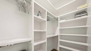 A walk-in closet with multiple shelves and hanging space, a wooden floor, and a visible trash bin. - South College Retreat - King + Office + Garage (Lafayette)