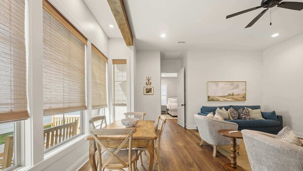 A spacious living area with a wooden dining table, chairs, a blue sofa, and a ceiling fan. - South College Retreat - King + Office + Garage (Lafayette)