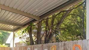 Un espace extérieur abrité, doté d’une clôture en bois peinte de motifs de tournesols.