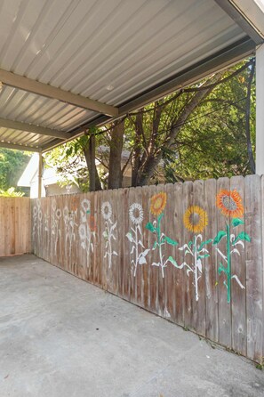 Un espacio al aire libre cubierto con una cerca de madera pintada con girasoles.