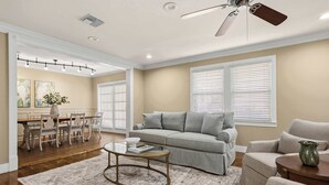 Un salon comprenant un canapé, des fauteuils, une table basse et un coin repas avec des chaises et une table.