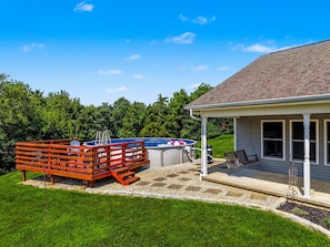 A backyard with a swimming pool, a wooden deck, and a covered patio area.