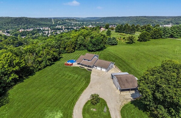 A large house with a swimming pool, surrounded by a well-maintained lawn and trees.