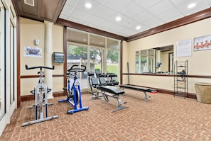 A gym with exercise equipment, a bench, and a mirror on the wall.