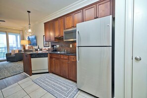 A kitchen with wooden cabinets, a stainless steel refrigerator, a microwave, and a dishwasher.